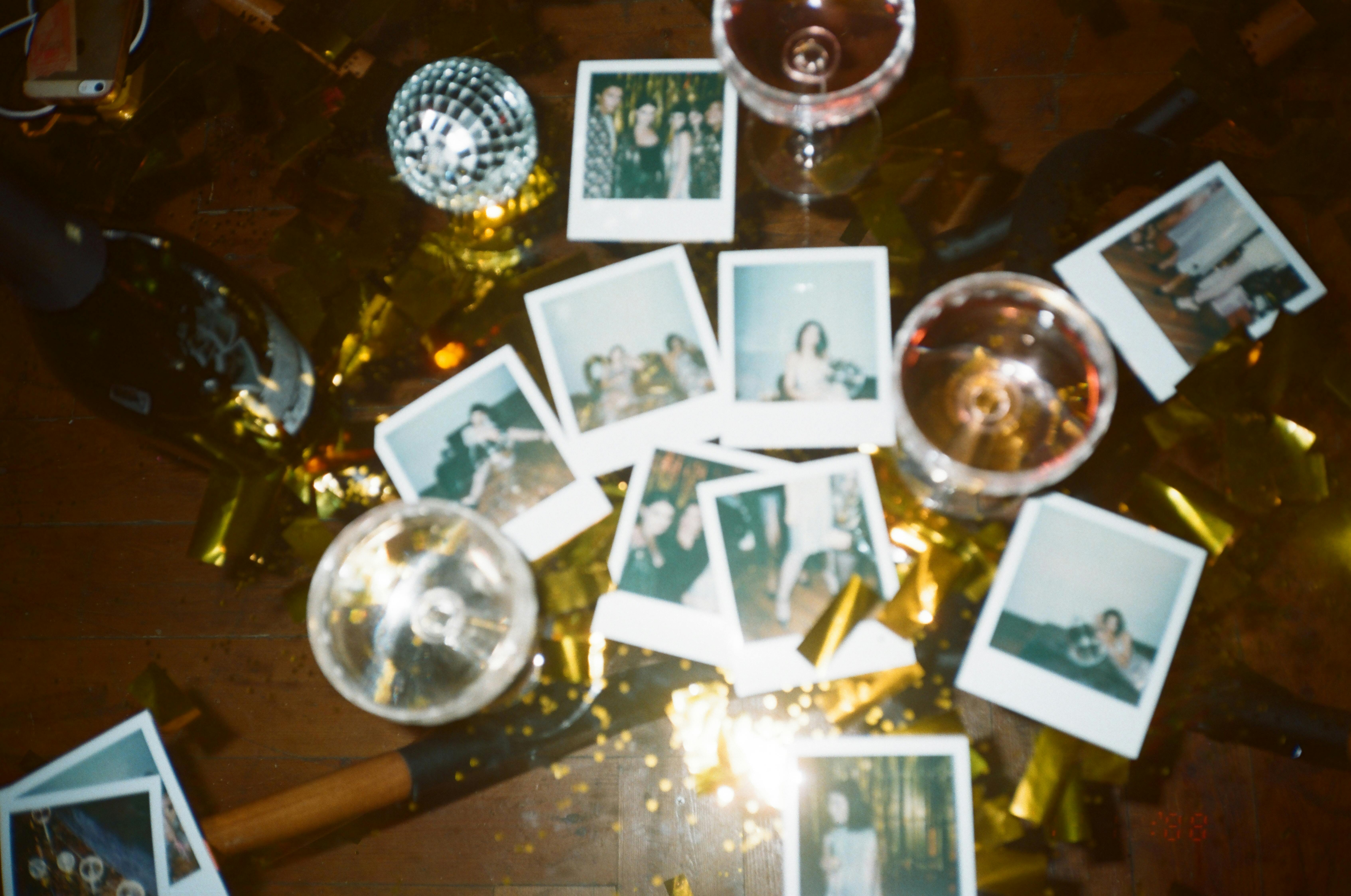 Scattered Polaroid photos, champagne glasses, and gold decorations on a festive holidays table