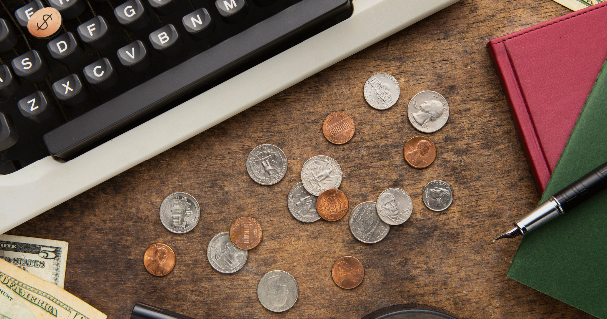 A desk with scattered coins, a typewriter, notebooks, and a pen, symbolizing financial planning and tax deductions in 2025.