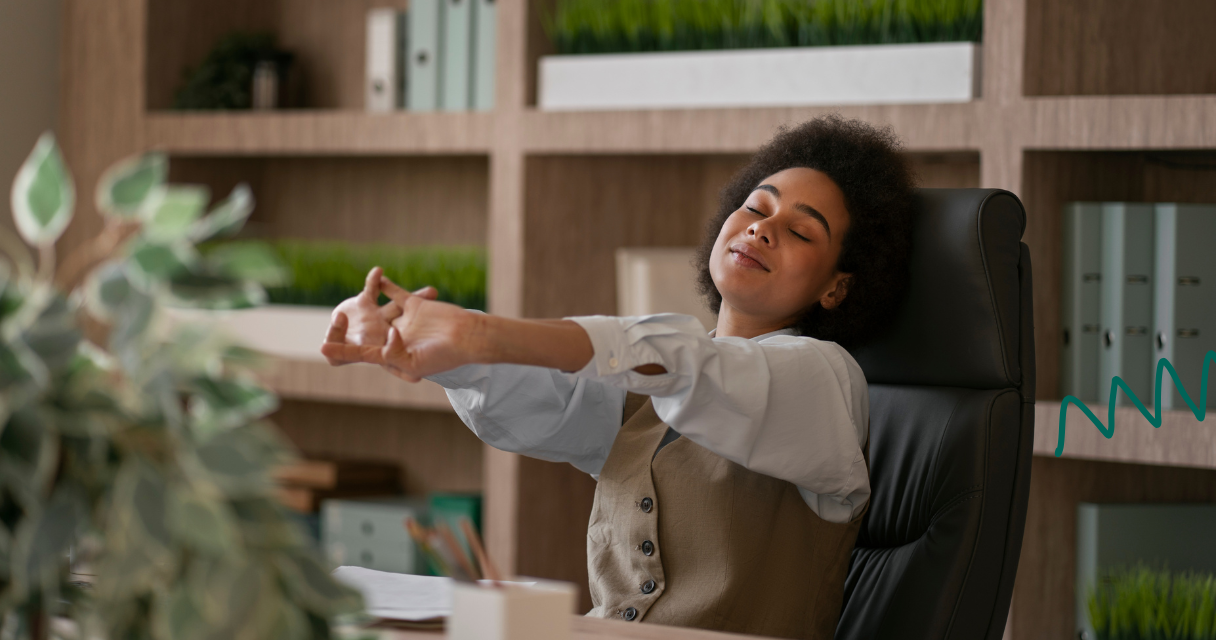Woman stretching at her desk in office showing relief and reduced workplace stress.
