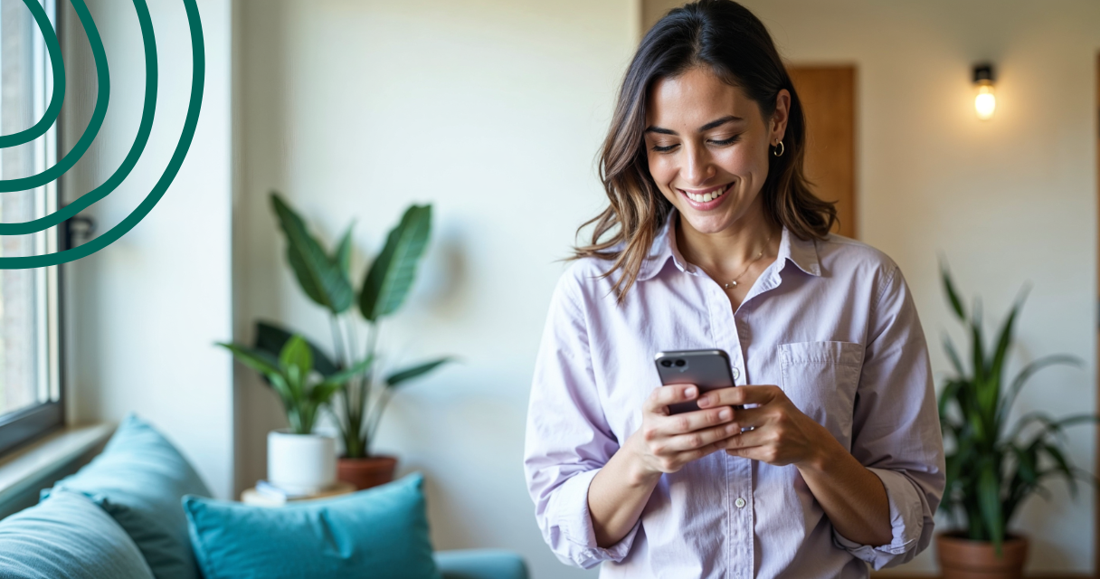 A smiling person checking their phone in a bright living room, representing confidence and understanding of how a cash advance works responsibly.